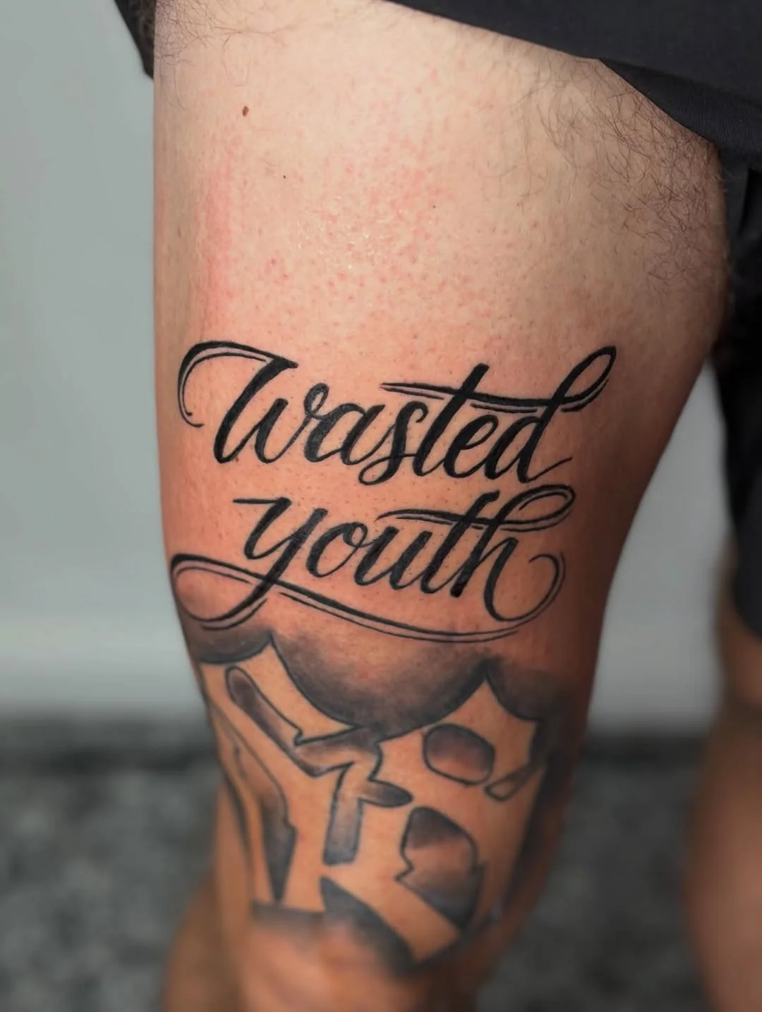 Lettering ‚Wasted Youth‘ auf dem Oberschenkel